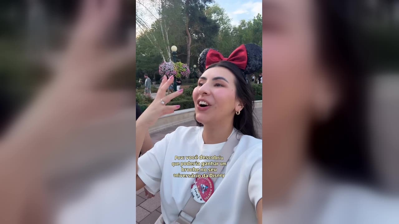 Karol Barbosa de orelhinha da Minnie mostrando o botton de aniversário da Disneyland Paris preso na camiseta