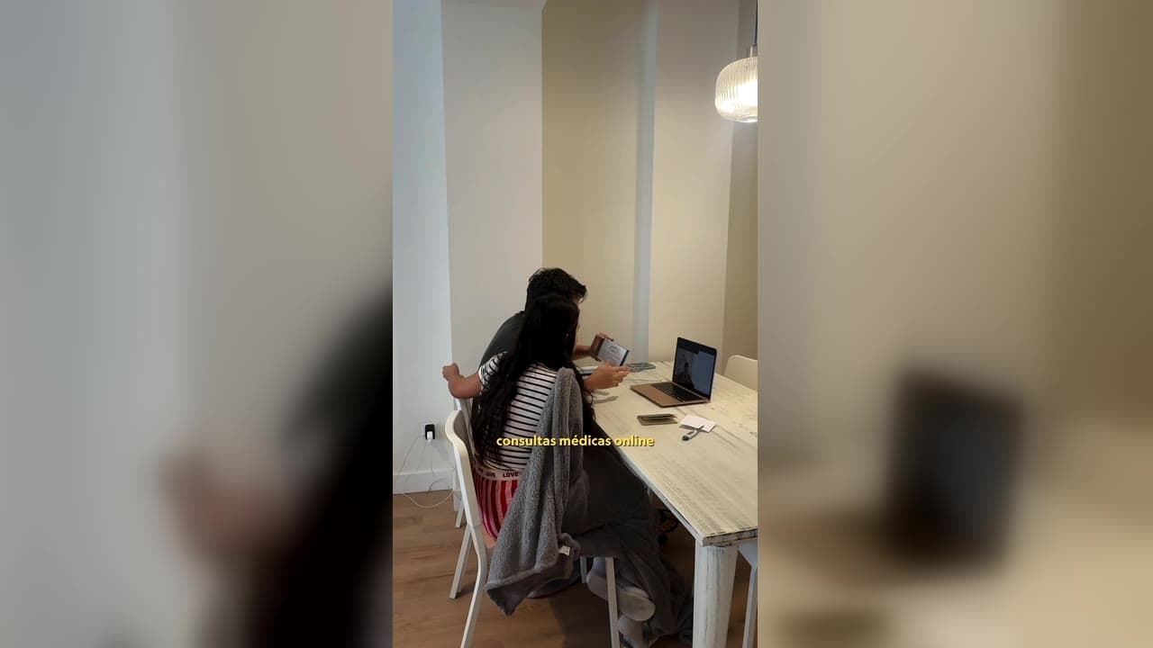 Karol e Red sentados à mesa diante de um notebook, numa consulta médica online